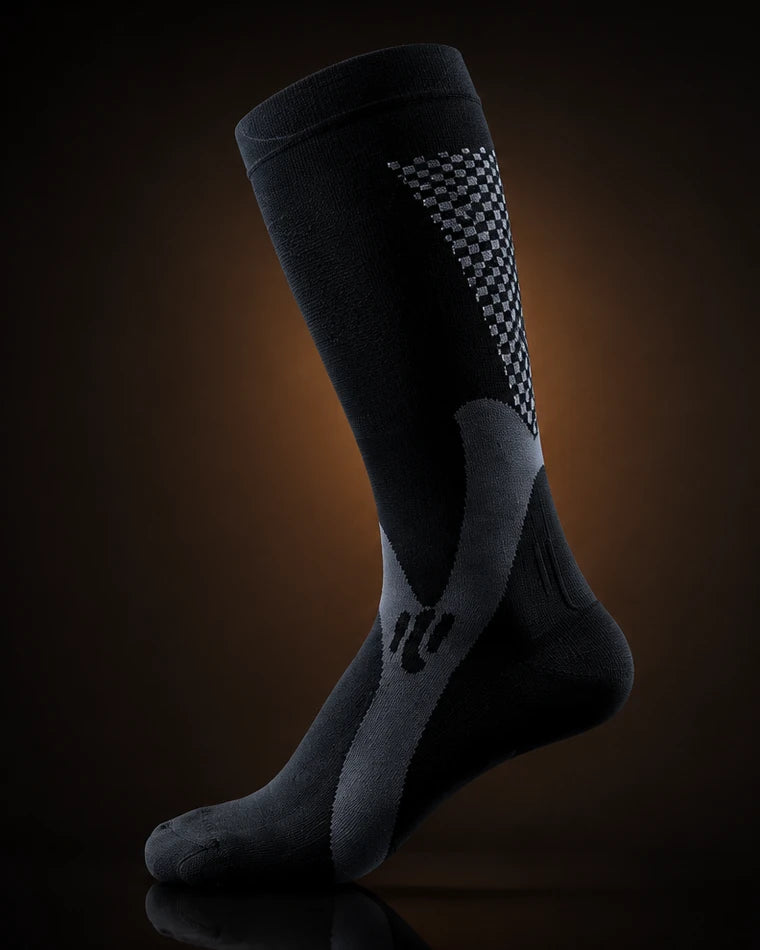 A knee-high VYLO compression sock photographed from the side, with seven numbered markers: the welt at the top, the jacquard panel on the calf, the calf zone, the ankle band, the heel, the toe, and the arch band on the sole.