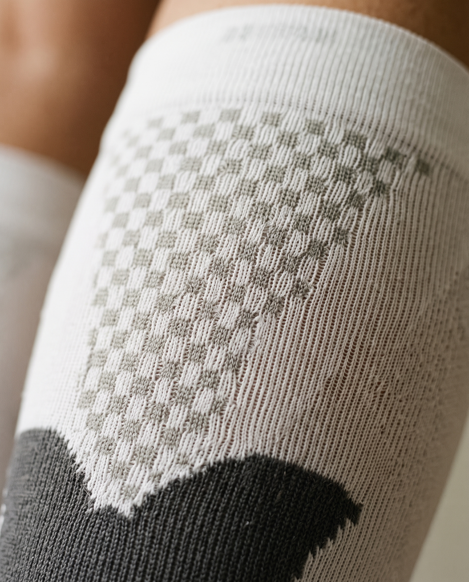 Macro close-up of the grey checkered mesh panel and compression knit on a Montrell compression sock